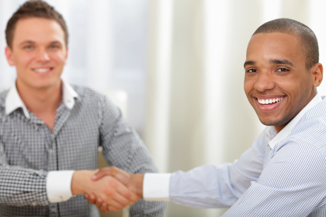 Homens sorrindo apertando as mão, fechando um negocio